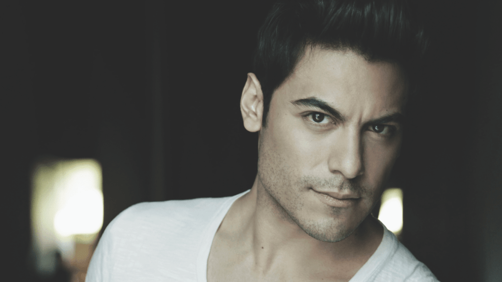 Retrato del cantante Carlos Rivera donde mira a cámara usando una camiseta blanca.